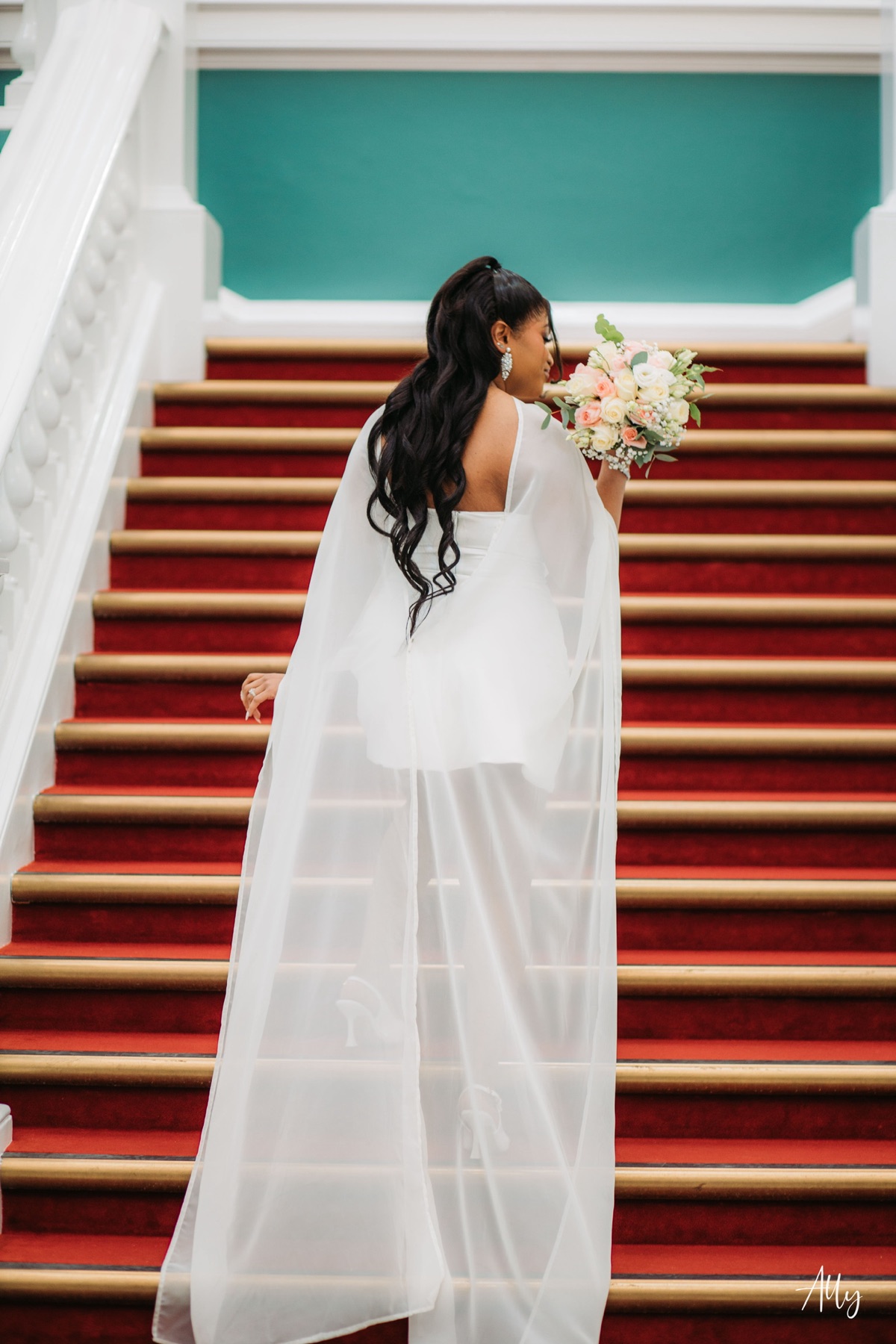Mercy holding her bouquet on the staircase